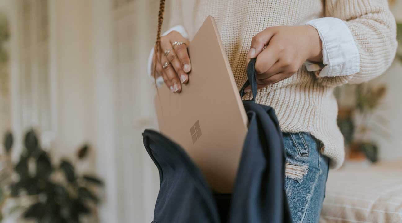 Une jeune femme pose un ordinateur portable dans son sac à dos bleu marin